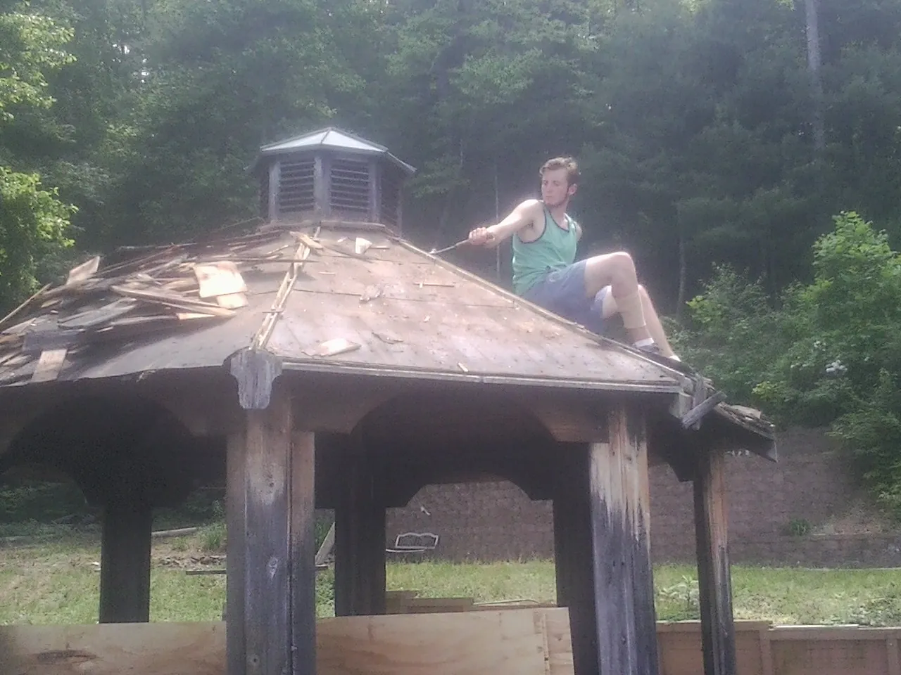 Tearing the old roof off a wooden gazebo before new shakes in De Leon Springs