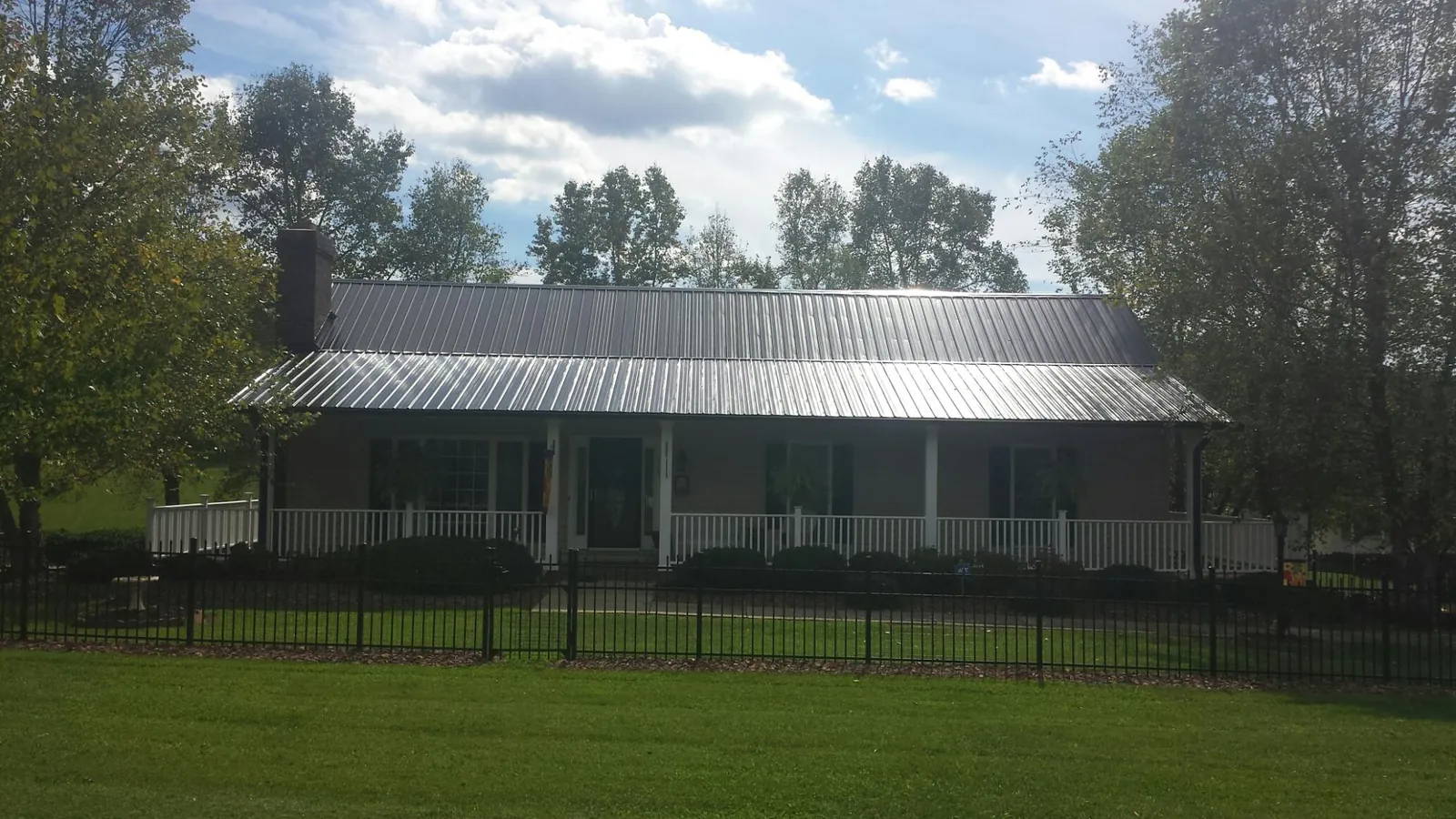 Gray metal roof on a brick ranch with a full width front porch — Gutter Guard Installation work by our crew in De Leon Springs