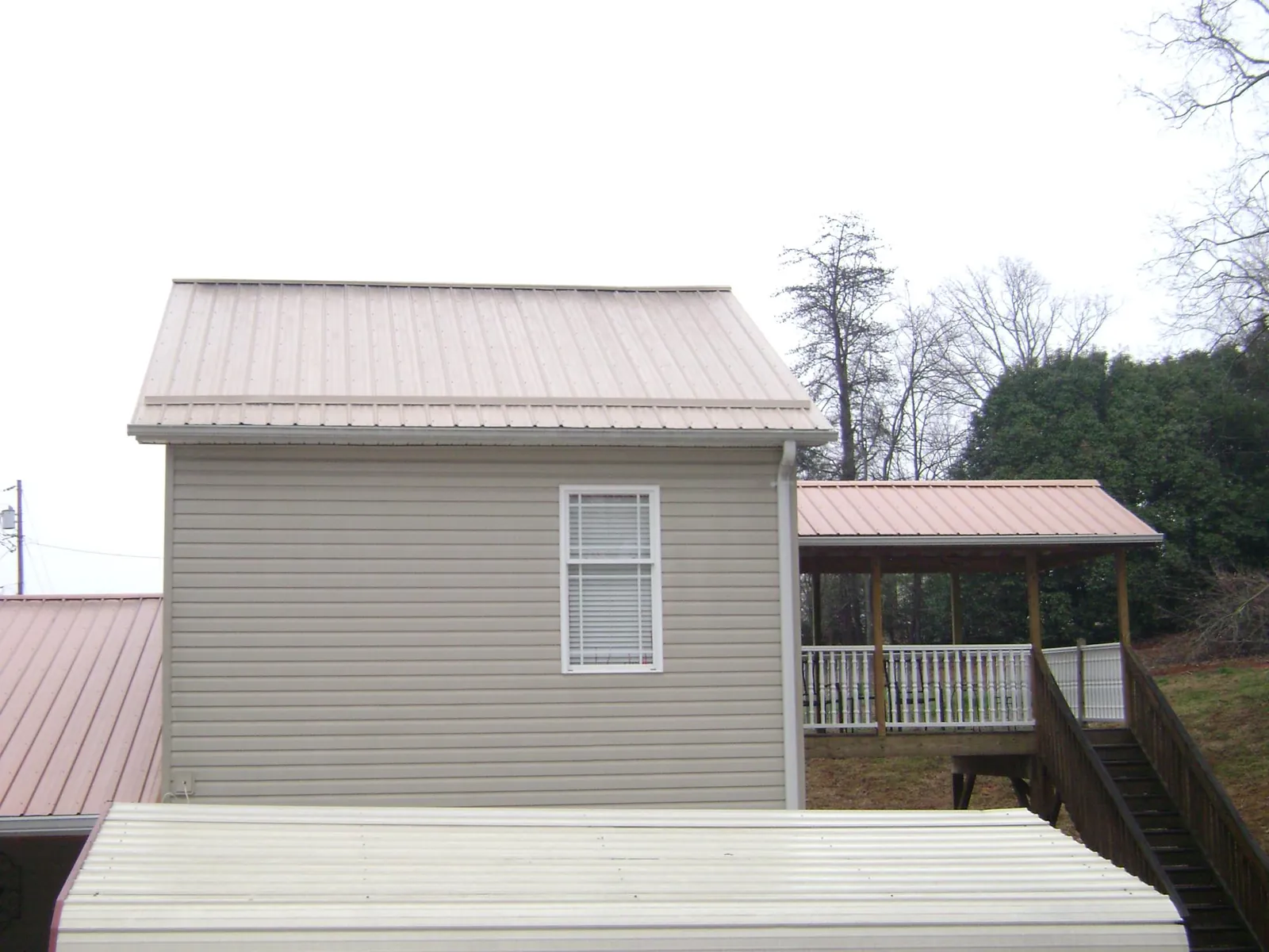 Tan metal roofs on a two story addition and attached porch, from a Roof Replacement job in De Leon Springs